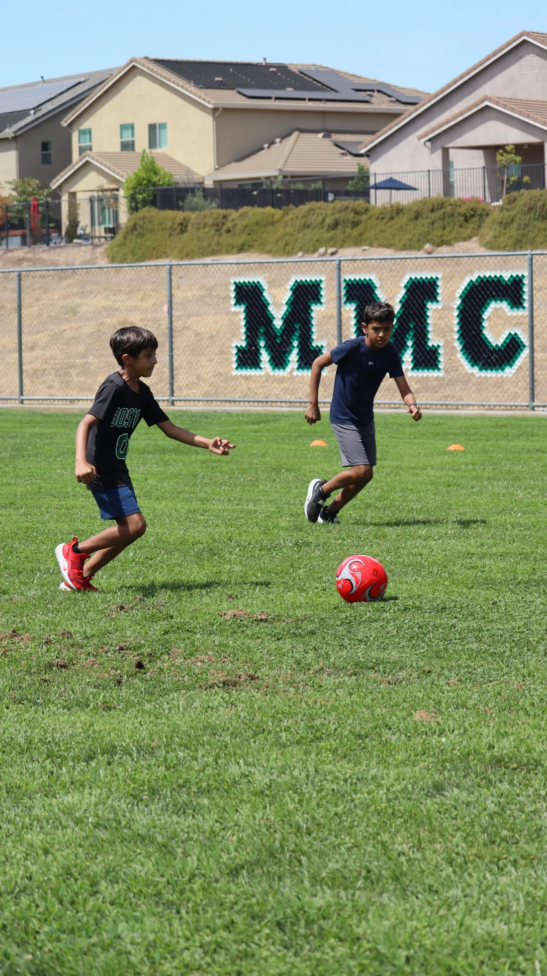 Two young athletes dribbling a soccer ball during training