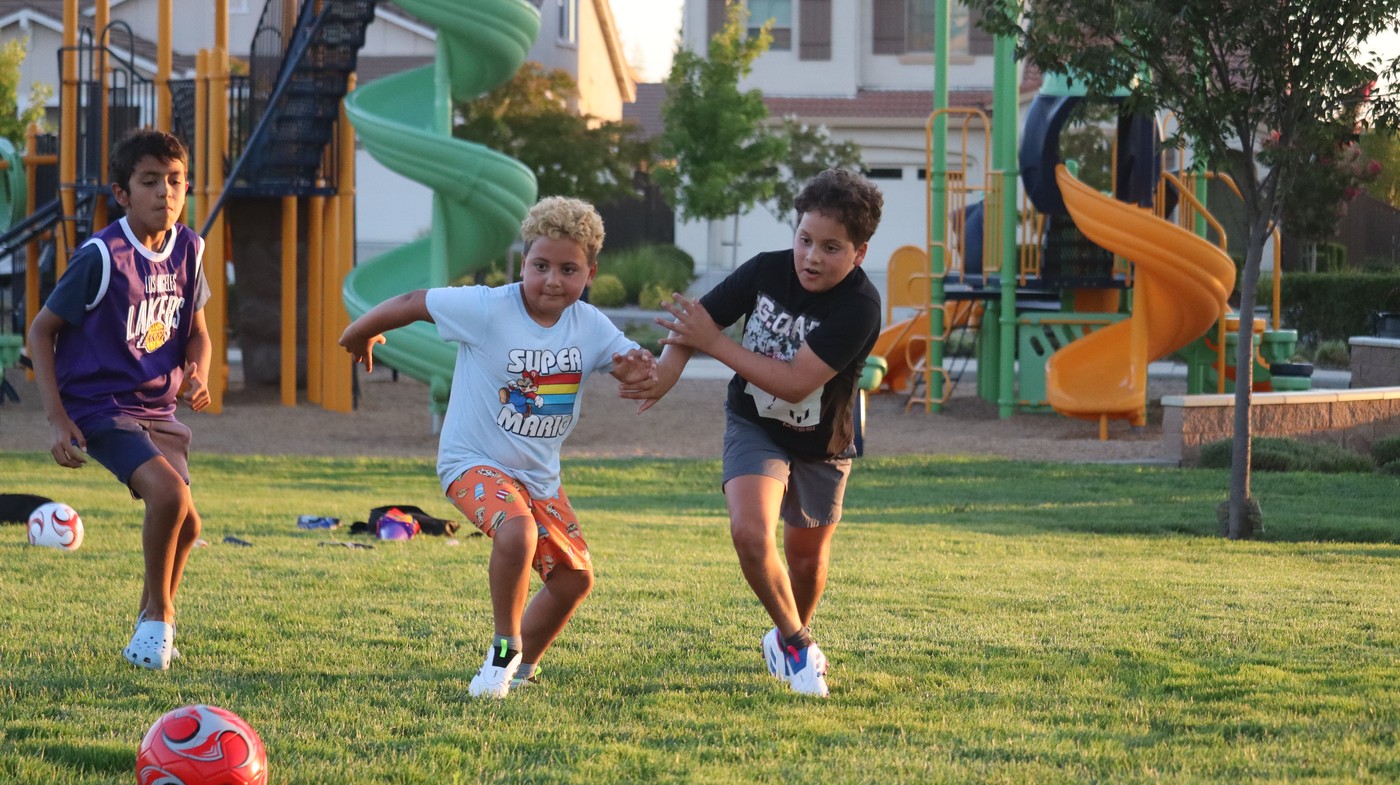 Soccer players competing for the ball near the playground